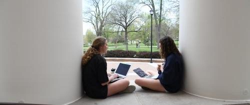 Students with laptops sitting in front of Crounse Hall